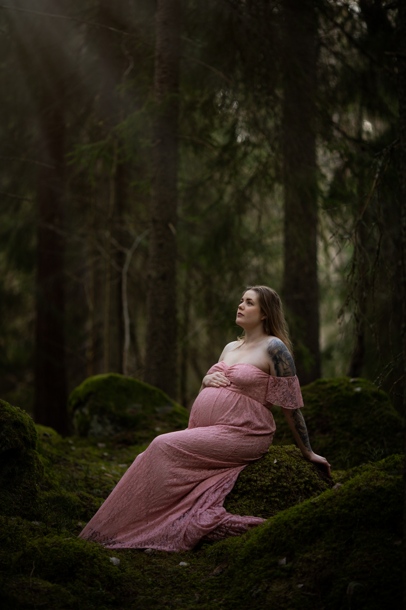 Studio-Li fotograferar en gravid kvinno på en bro som blickar ut